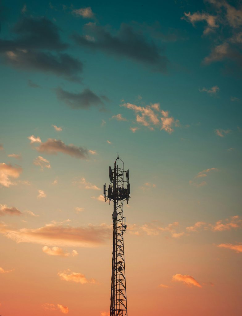 A communication tower silhouetted against a colorful sunset sky in Cruzeiro, Brazil.